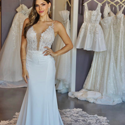 Ivory wedding gown Tessa with lace detailing on sheer mesh bodice with plunging v-neckline. Sheer sides and hip detail. Unembellished ivory skirt with lace train.