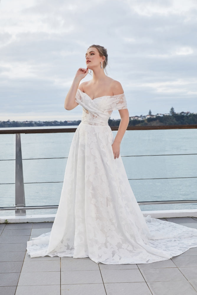 Teresa gown. Sheer floral organza fabric with sweetheart neckline that crosses over the bust and ruches at the side seams. Full A-line skirt with soft flowing train.