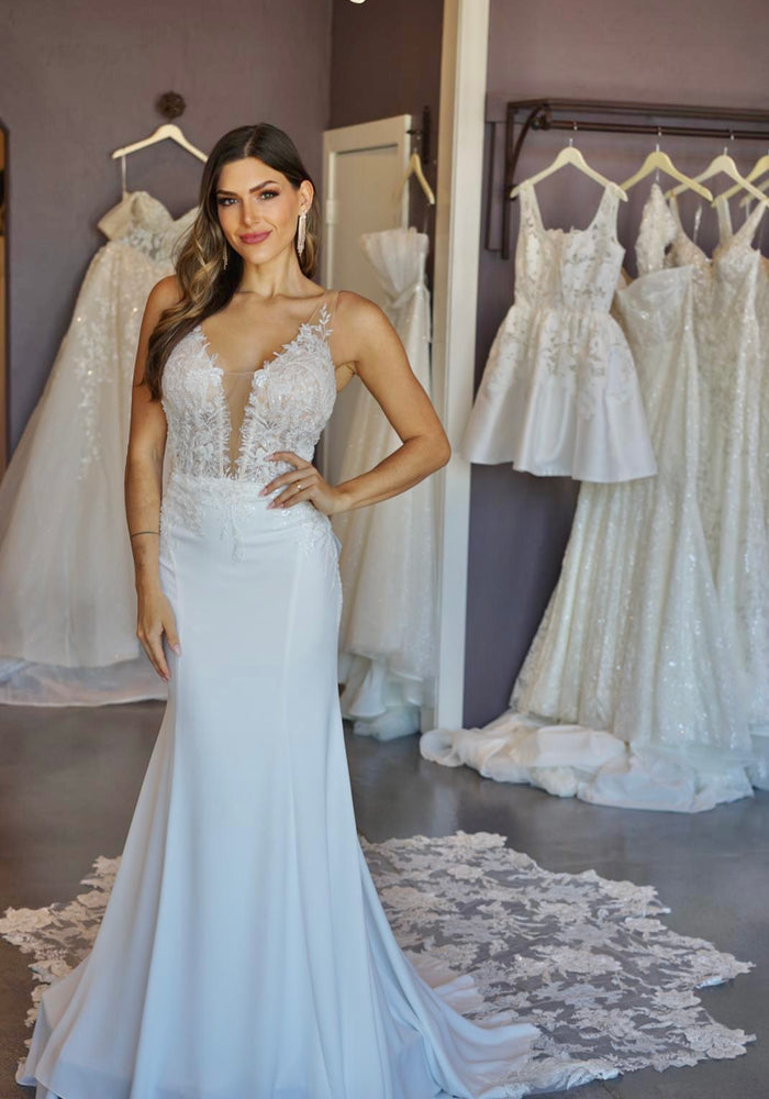 Ivory wedding gown Tessa with lace detailing on sheer mesh bodice with plunging v-neckline. Sheer sides and hip detail. Unembellished ivory skirt with lace train.