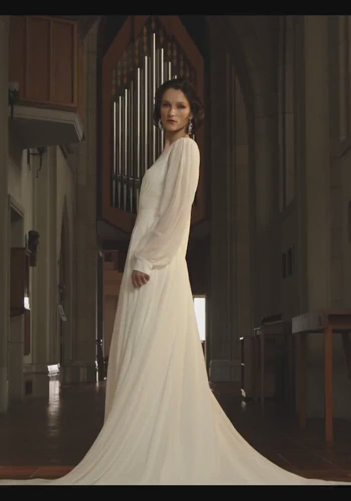 Model wearing Serena wedding dress with long sleeves and a flowing skirt from the Royal collection