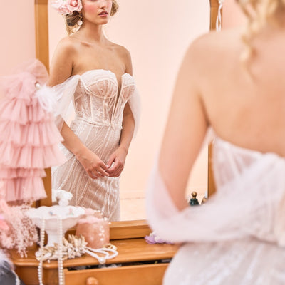 Model wearing fit-n-flare Sierra wedding dress with tulle off-shoulder sleeves from the Mademoiselle collection