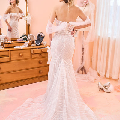 Model wearing fit-n-flare Sierra wedding dress with tulle off-shoulder sleeves from the Mademoiselle collection