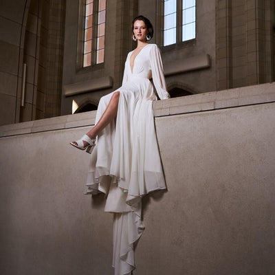 Model wearing Serena wedding dress with long sleeves and a flowing skirt from the Royal collection