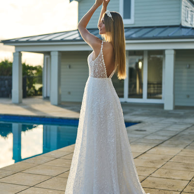 Back view of Penelope gown. Beaded daisy chain continue over the shoulders and down the V back. Soft a-line skirt with subtle train and gently structured hem.
