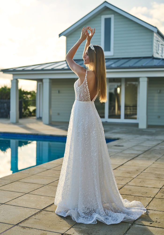 Back view of Penelope gown. Beaded daisy chain continue over the shoulders and down the V back. Soft a-line skirt with subtle train and gently structured hem.