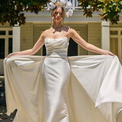 Model wears lisha gown, strapless, off-the-shoulder, fit-n-flare, mikado fabric, full length train with Overskirt.