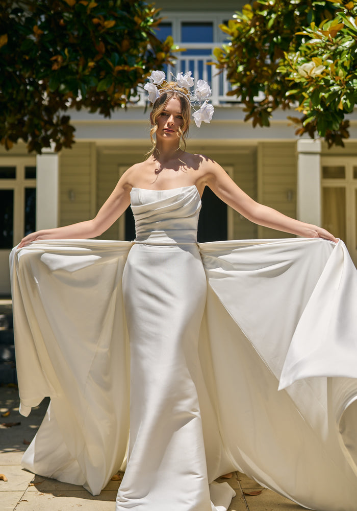 Model wears lisha gown, strapless, off-the-shoulder, fit-n-flare, mikado fabric, full length train with Overskirt.