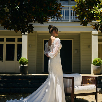 Bride wears primrose gown. Back view with draped train and organza balloon sleeves